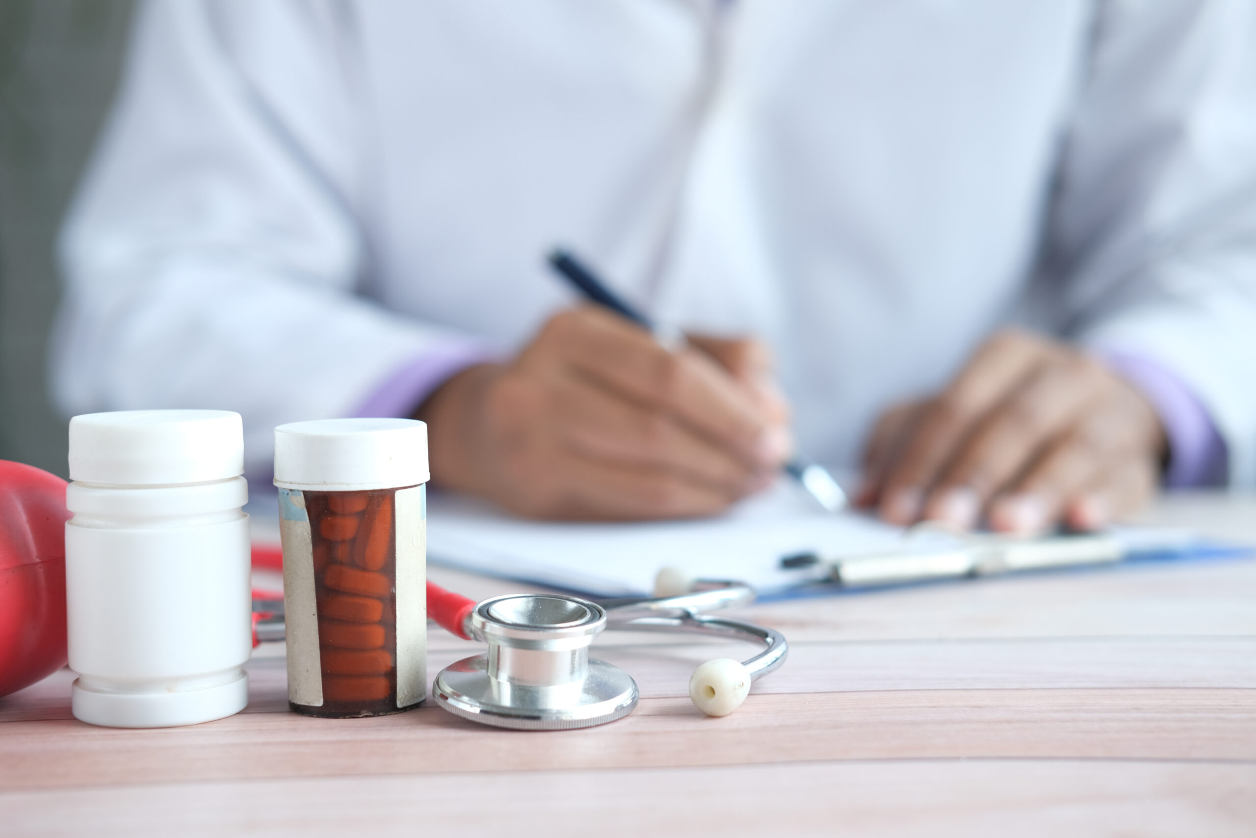 doctor hand writing prescription on desk, close up.